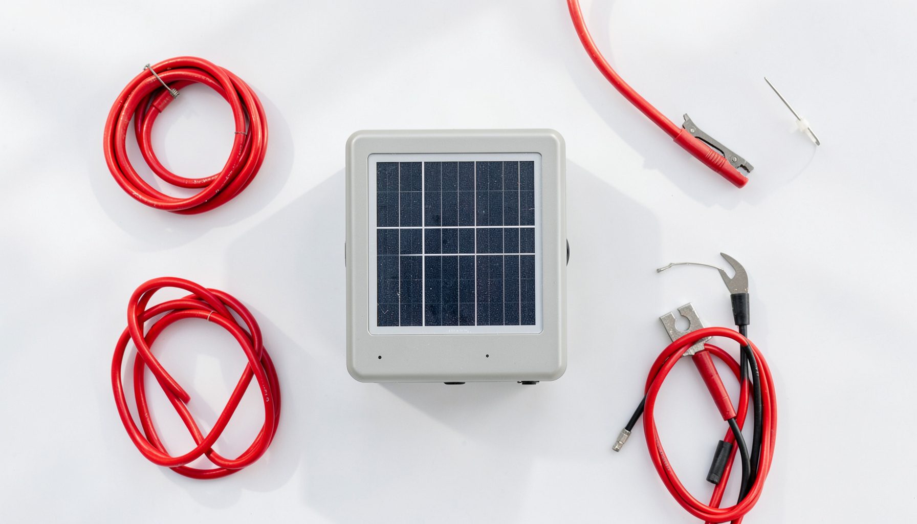 Overhead flat-lay photograph of a modern photovoltaic inverter on a clean white surface, surrounded by neatly arranged solar installation tools and cables, with natural daylight casting soft shadows across the scene.